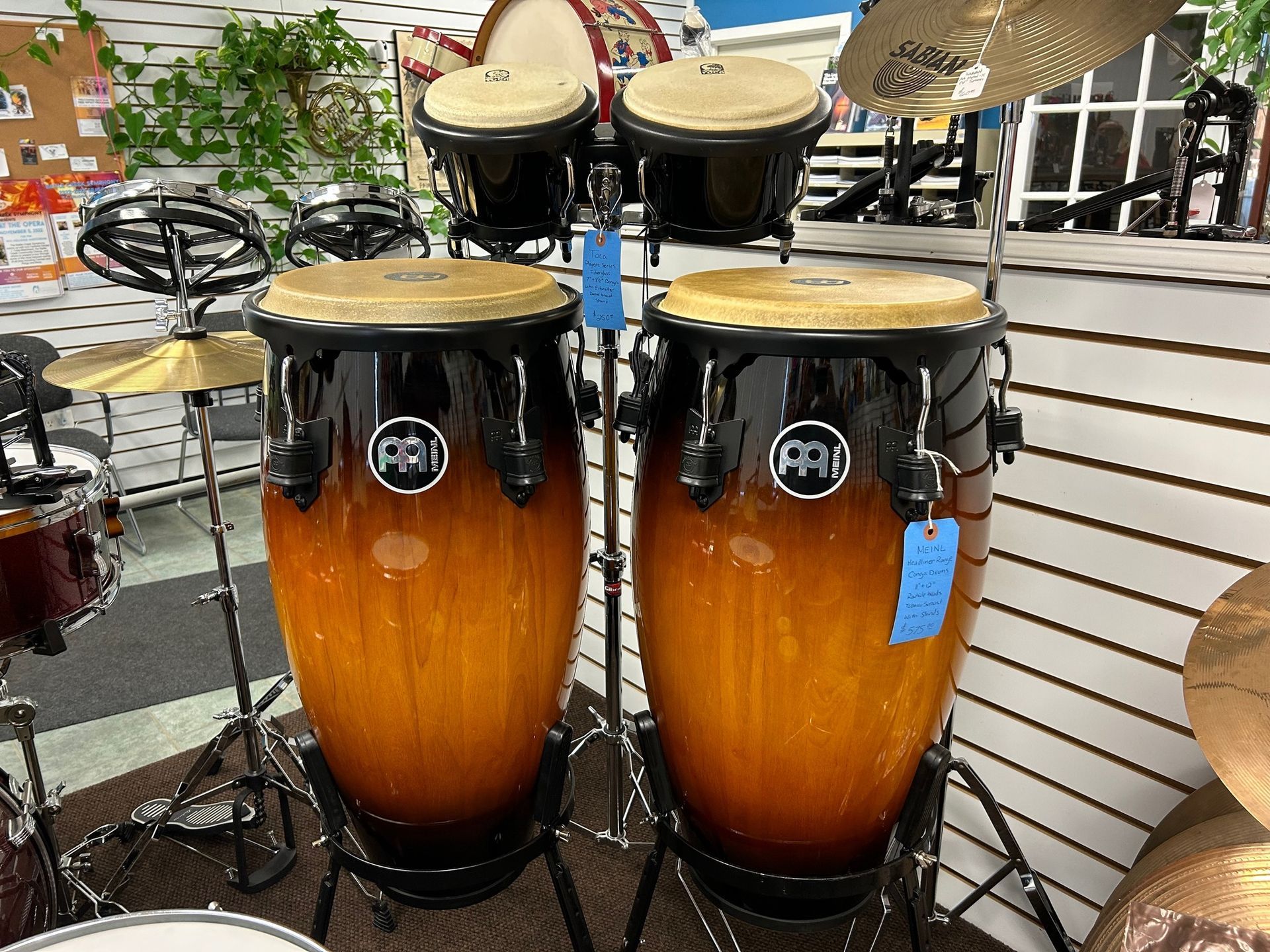 Two conga drums with a black and amber finish, displayed in a music store.