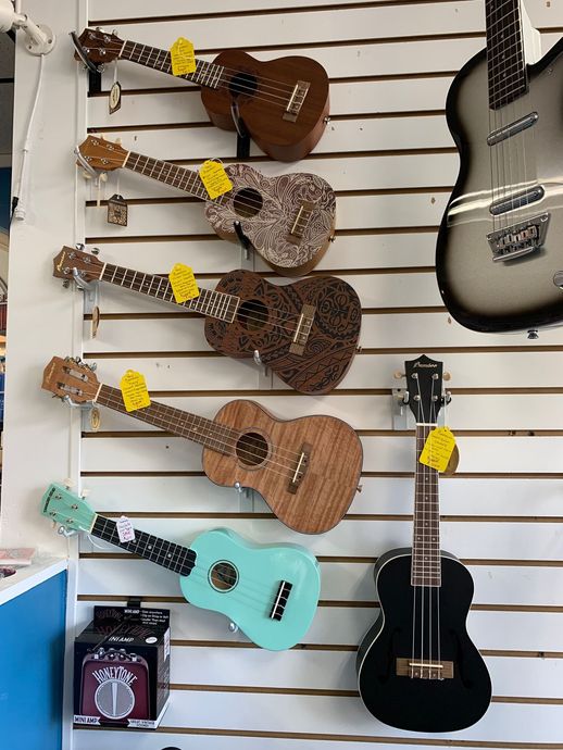 Wall display of ukuleles in various colors and a single guitar.