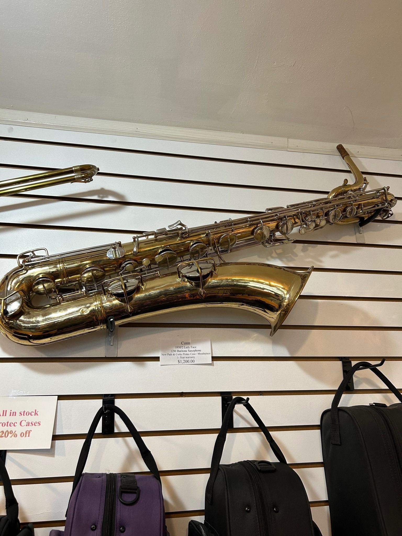 Golden saxophone hanging on a wall with bags below.
