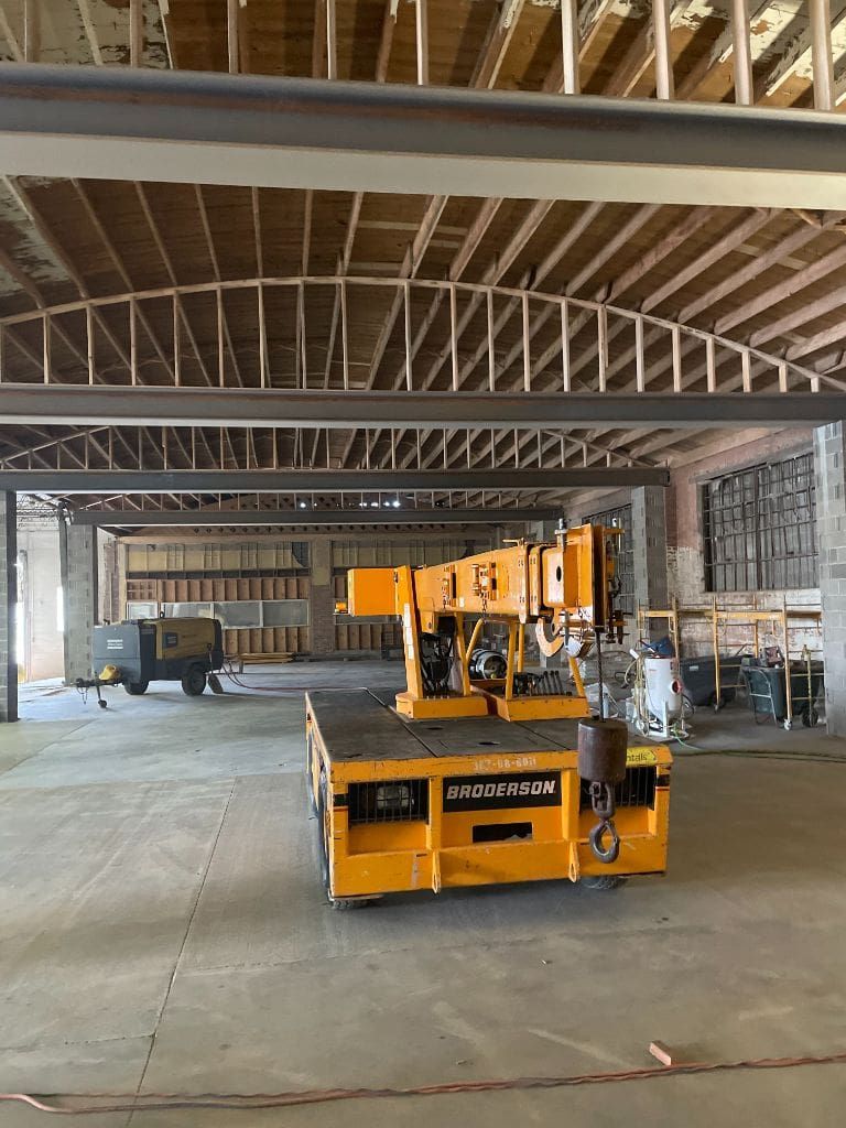 A yellow truck is parked in a large warehouse under construction.