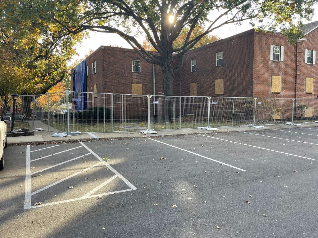 A parking lot with a fence around it and a brick building in the background