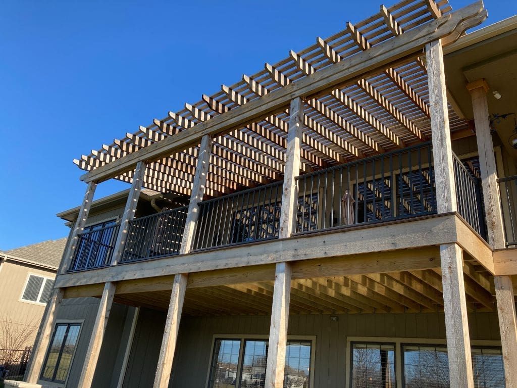 A large wooden deck with a pergola on top of it.