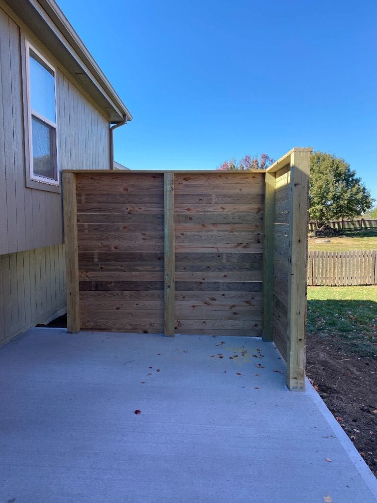 A wooden fence is sitting in the backyard of a house.