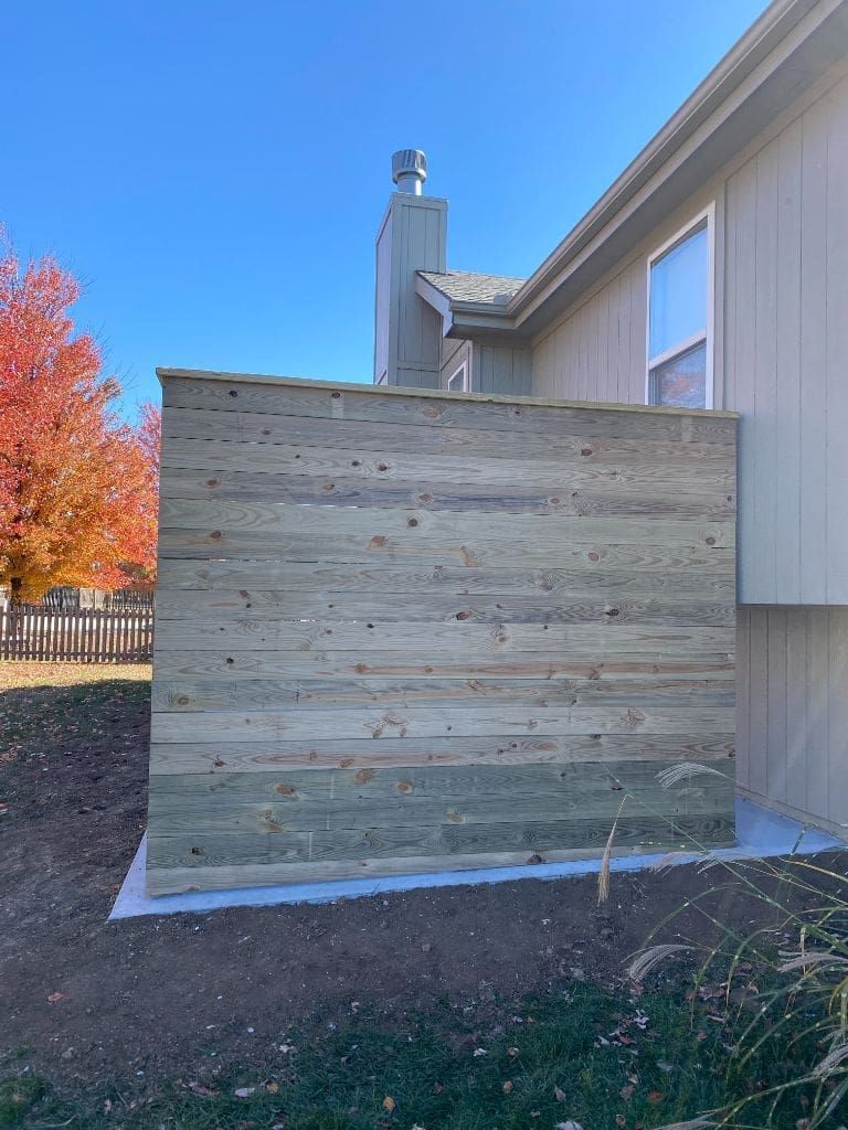 A wooden fence is sitting in front of a house.