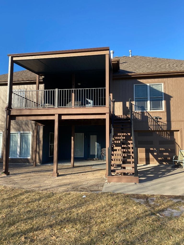 The back of a house with a large deck and stairs.