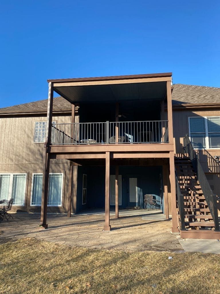 The back of a house with a large deck and stairs.