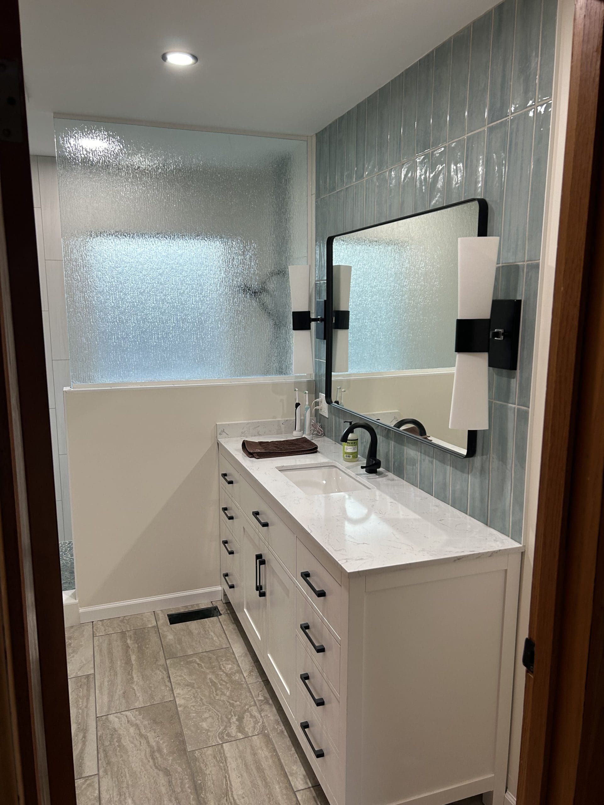 A bathroom with a sink , mirror and shower.