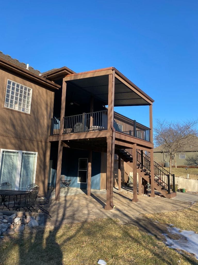 The back of a house with a large deck and stairs.