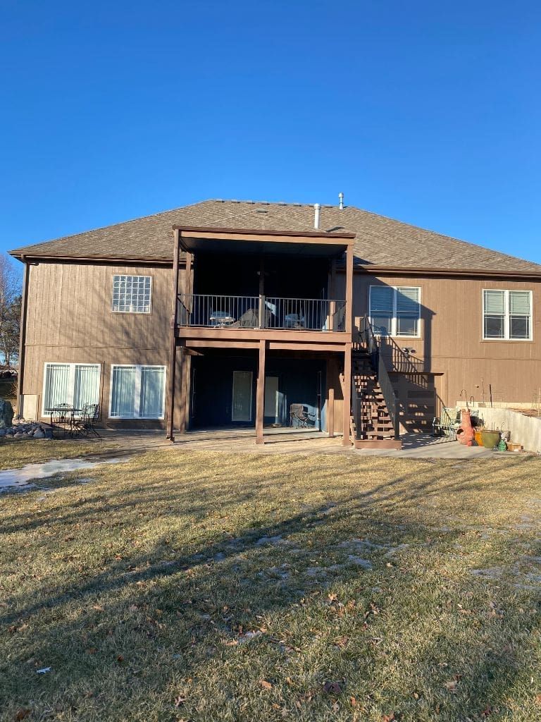 The back of a house with a large deck and stairs.