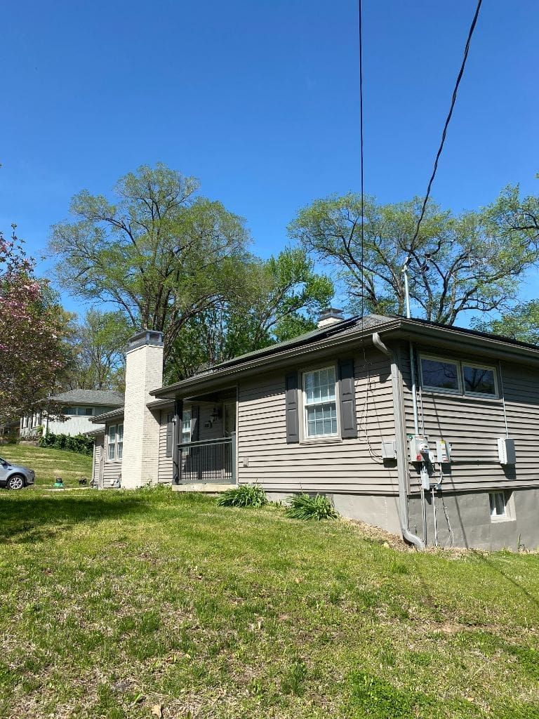 A small house is sitting on top of a lush green hill.