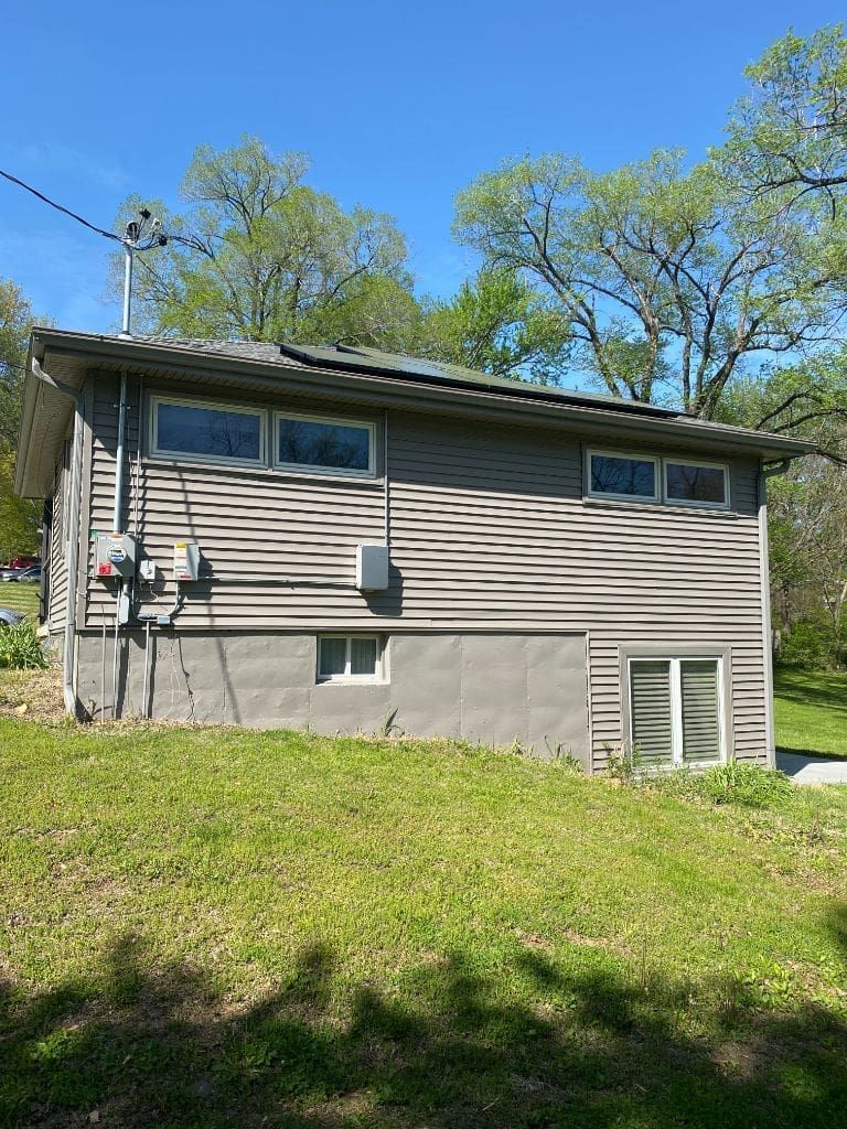 A small house with a lot of windows is sitting on top of a lush green field.