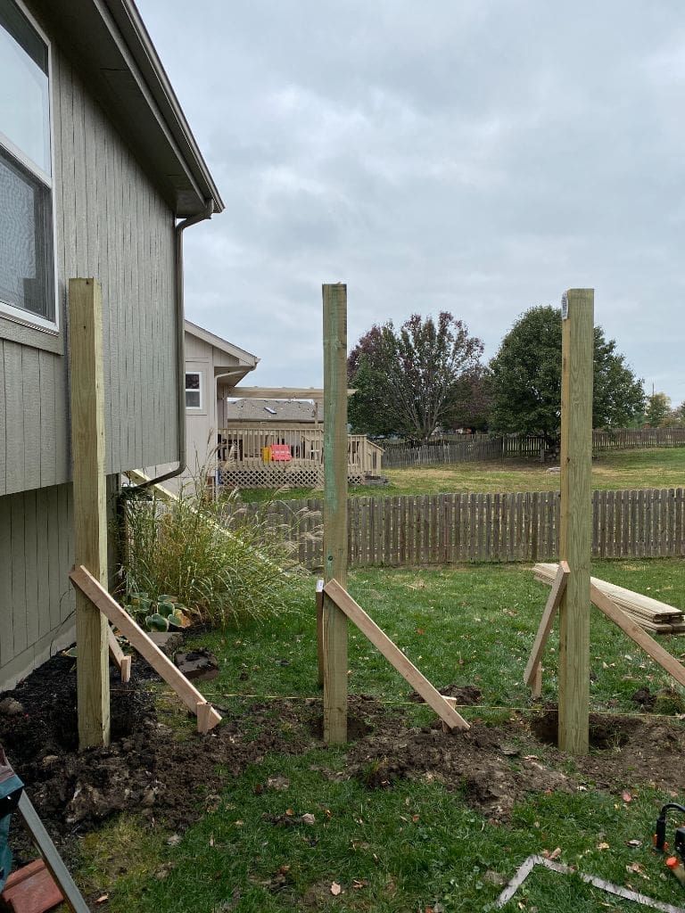 A wooden fence is being built in the backyard of a house.
