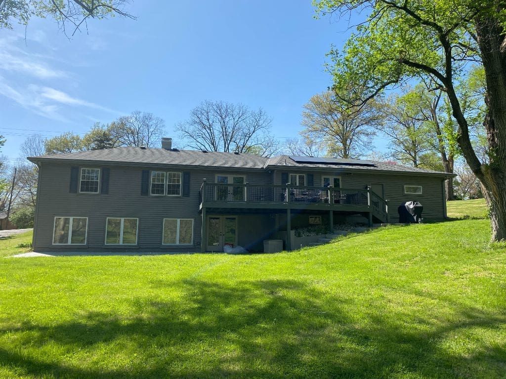 A large house is sitting on top of a lush green hill.