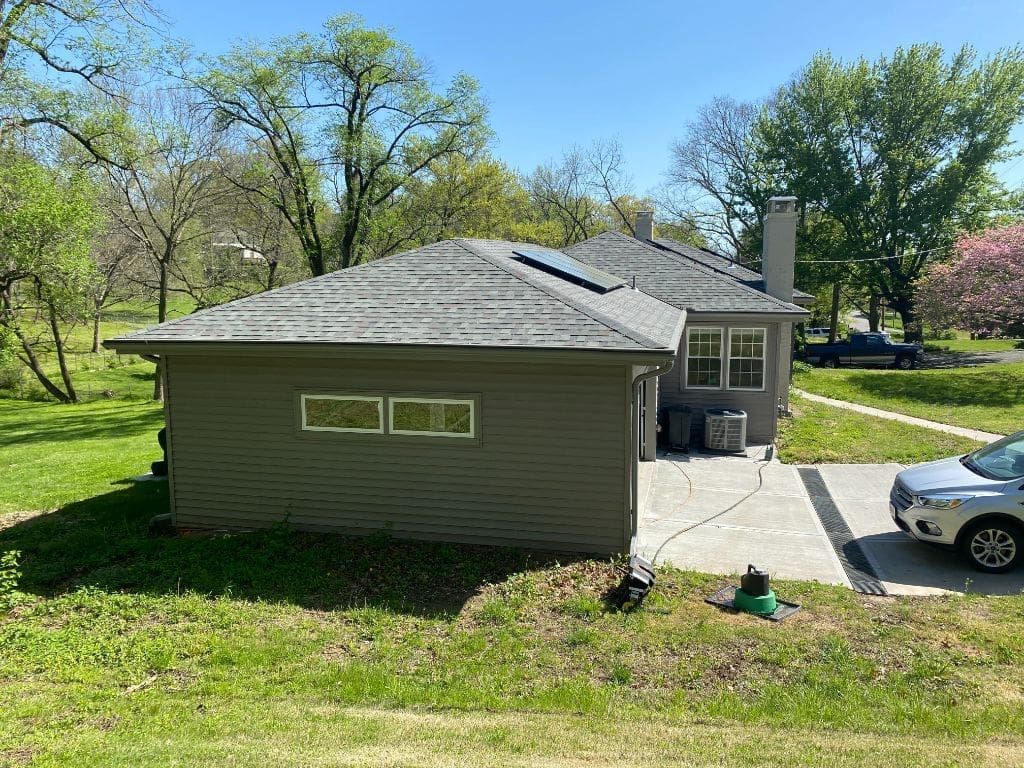 A car is parked in front of a house on a sunny day.