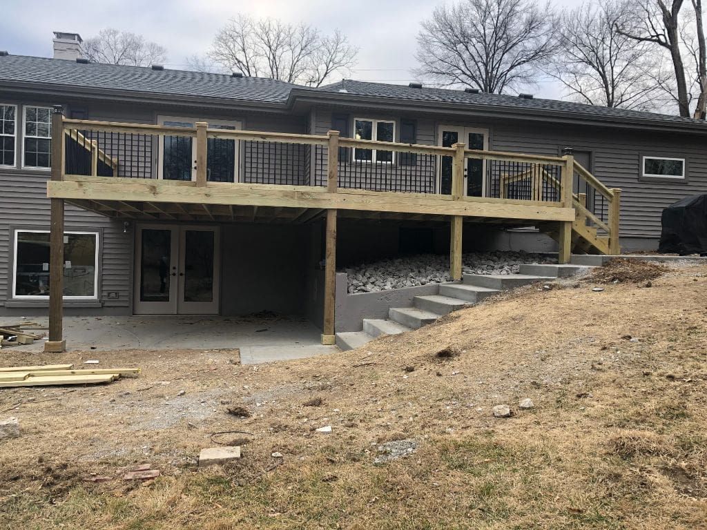 A large wooden deck is being built on the back of a house.