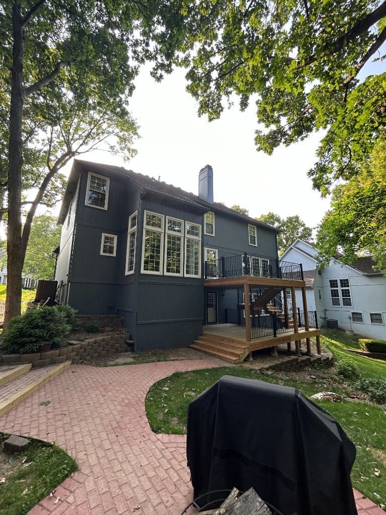 The back of a house with a brick walkway and a deck.