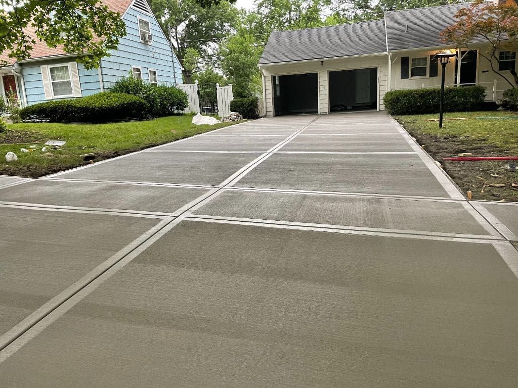 A concrete driveway leading to a house with a garage.