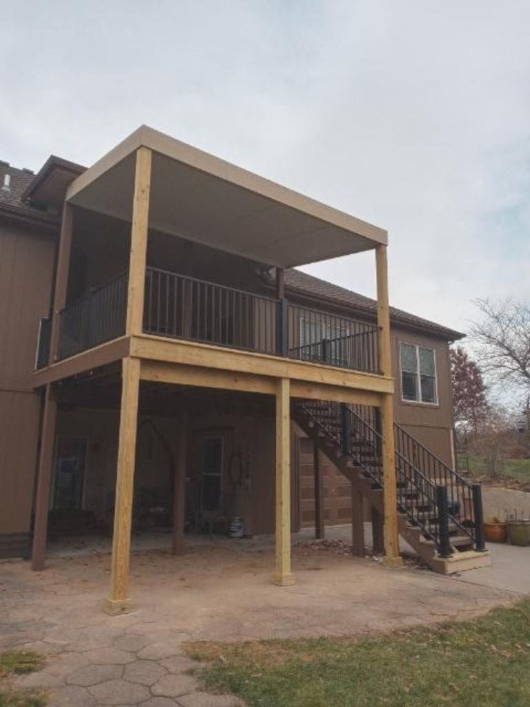 A house with a wooden deck and stairs in front of it.