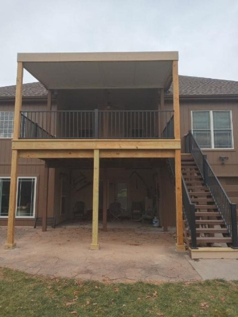 The back of a house with a wooden deck and stairs.