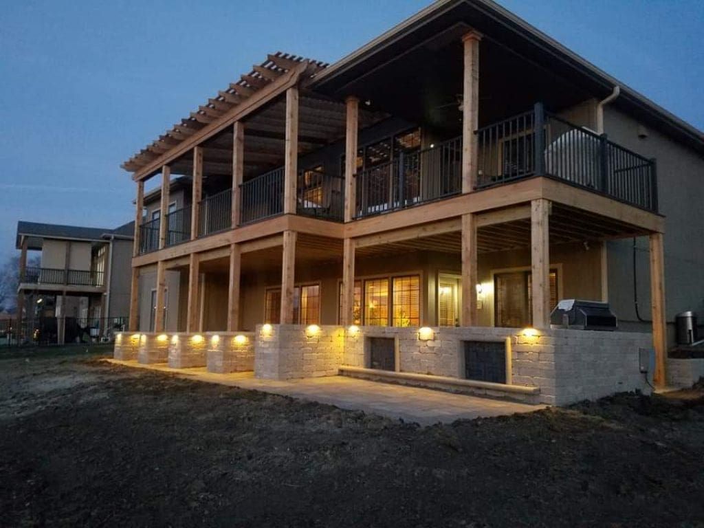 A large house with a large deck is lit up at night.