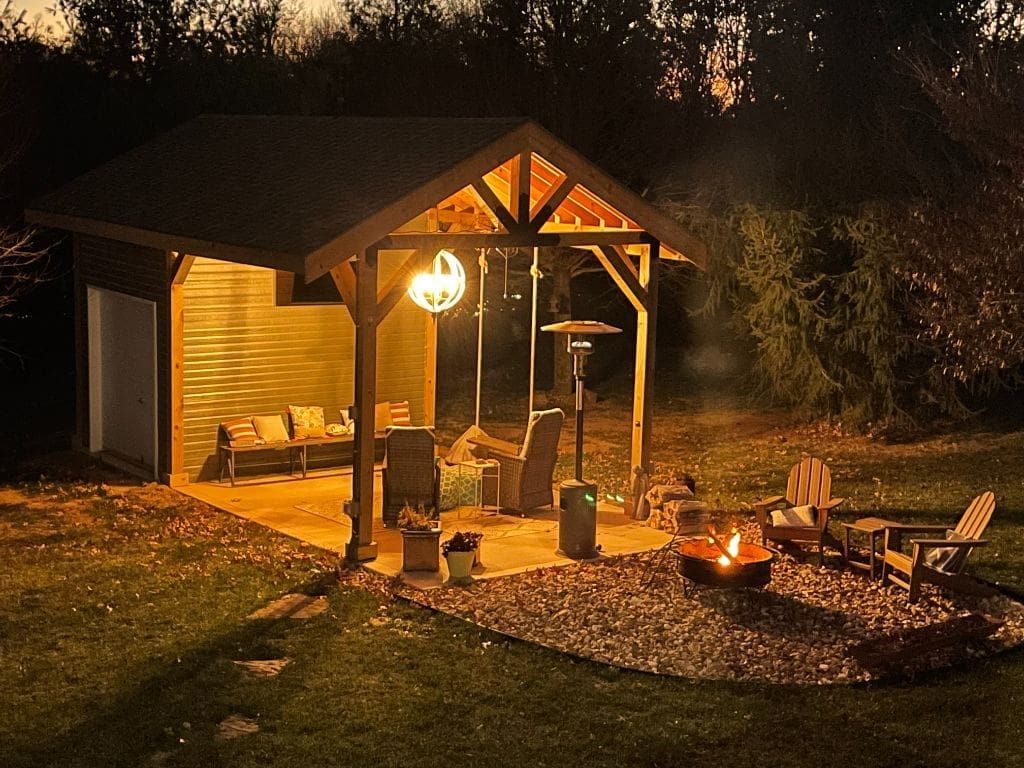 A gazebo with a fire pit in front of it is lit up at night.