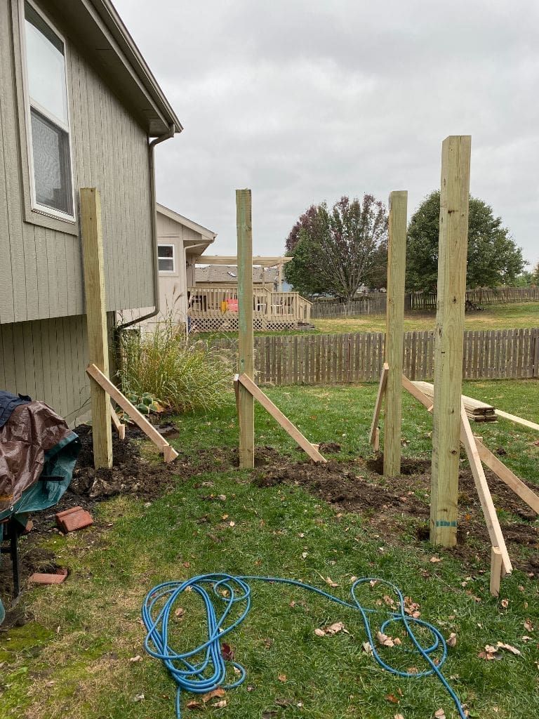A wooden fence is being built in the backyard of a house.