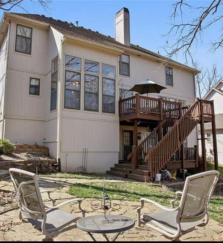 A large white house with a wooden deck and stairs