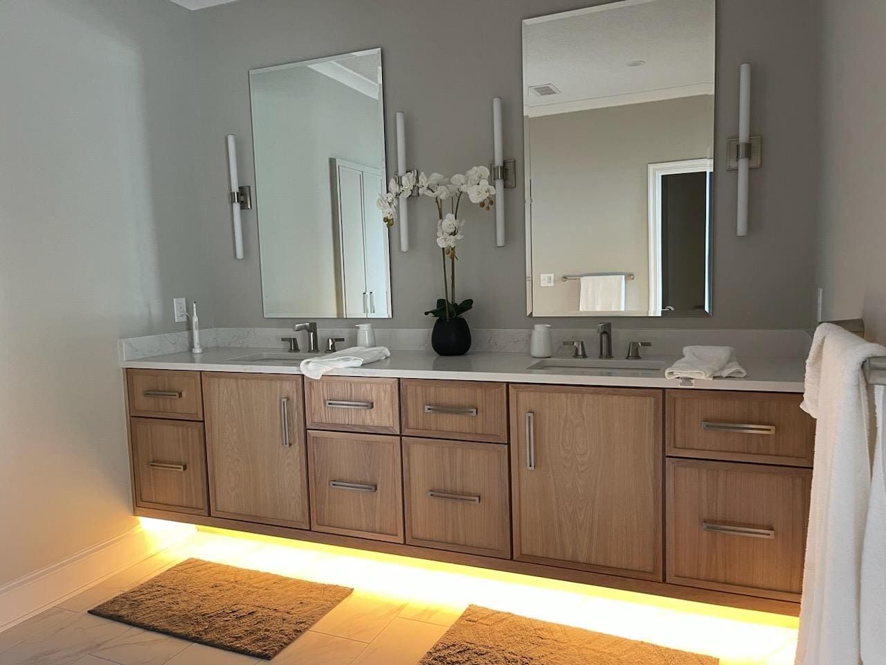 A bathroom with two sinks , two mirrors , and wooden cabinets.