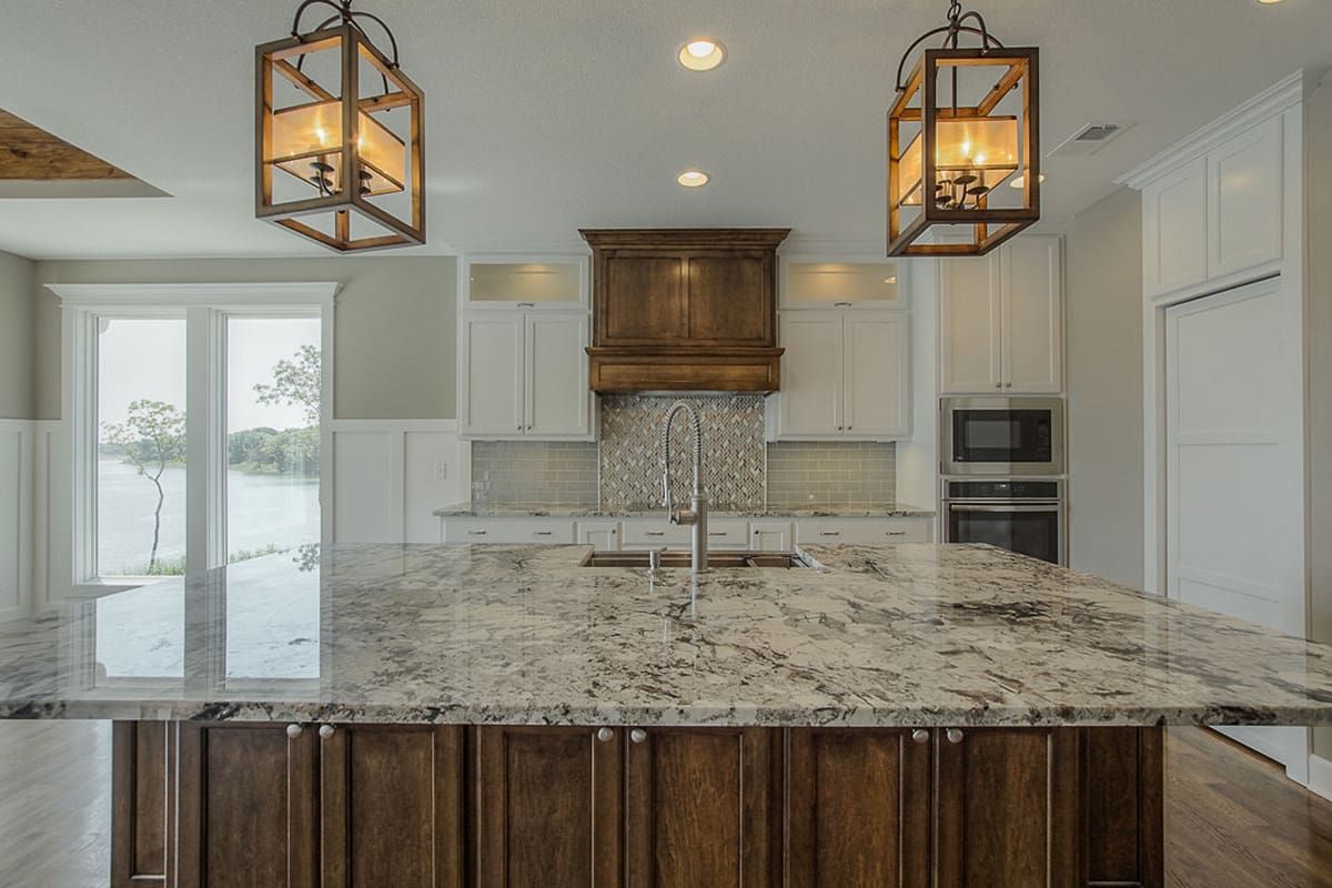 A kitchen with a large island and granite counter tops.