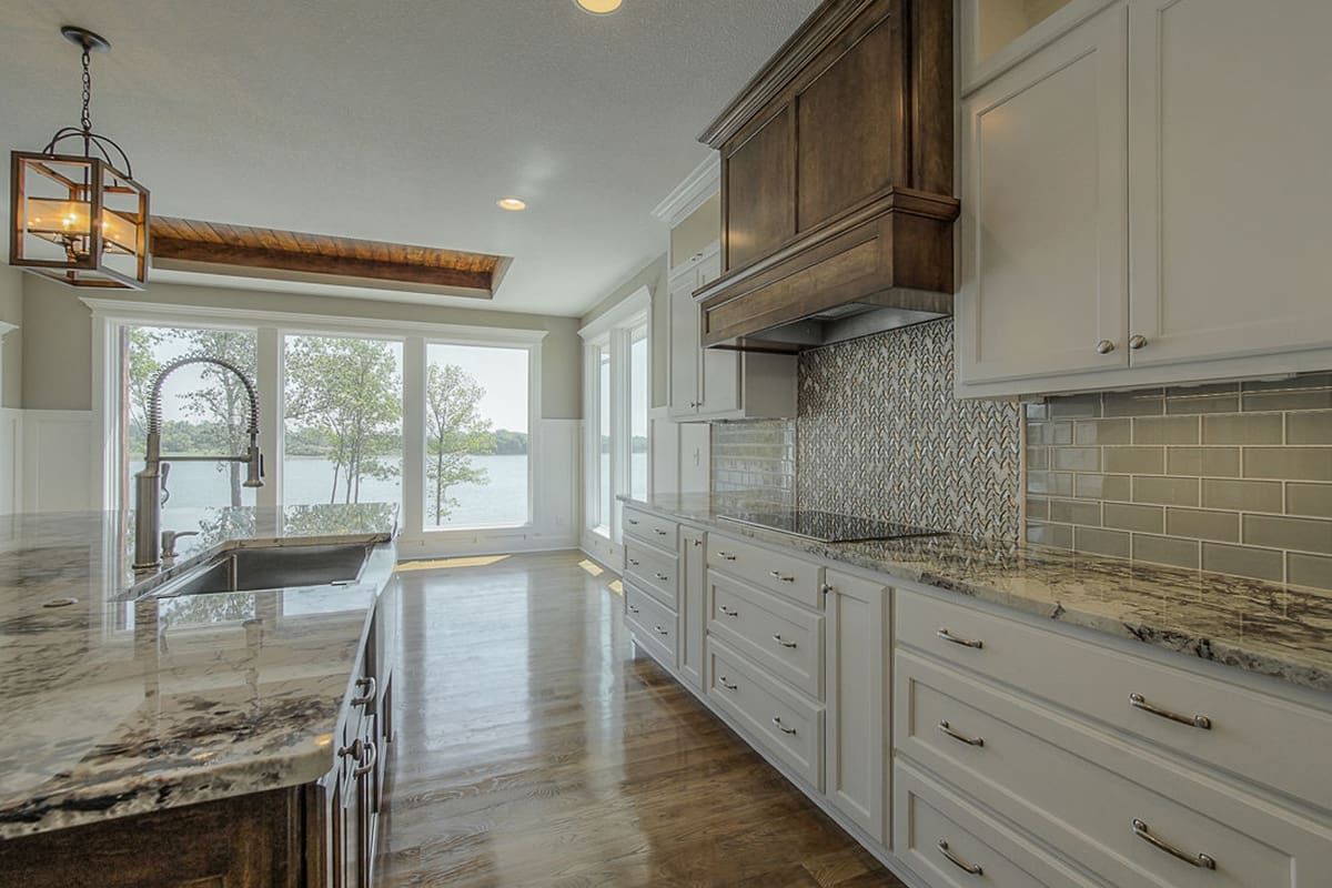 A kitchen with white cabinets , granite counter tops , and a sink.