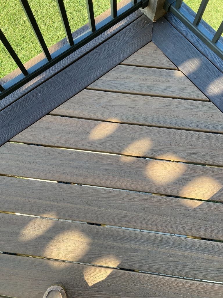 A close up of a wooden deck with a black railing.