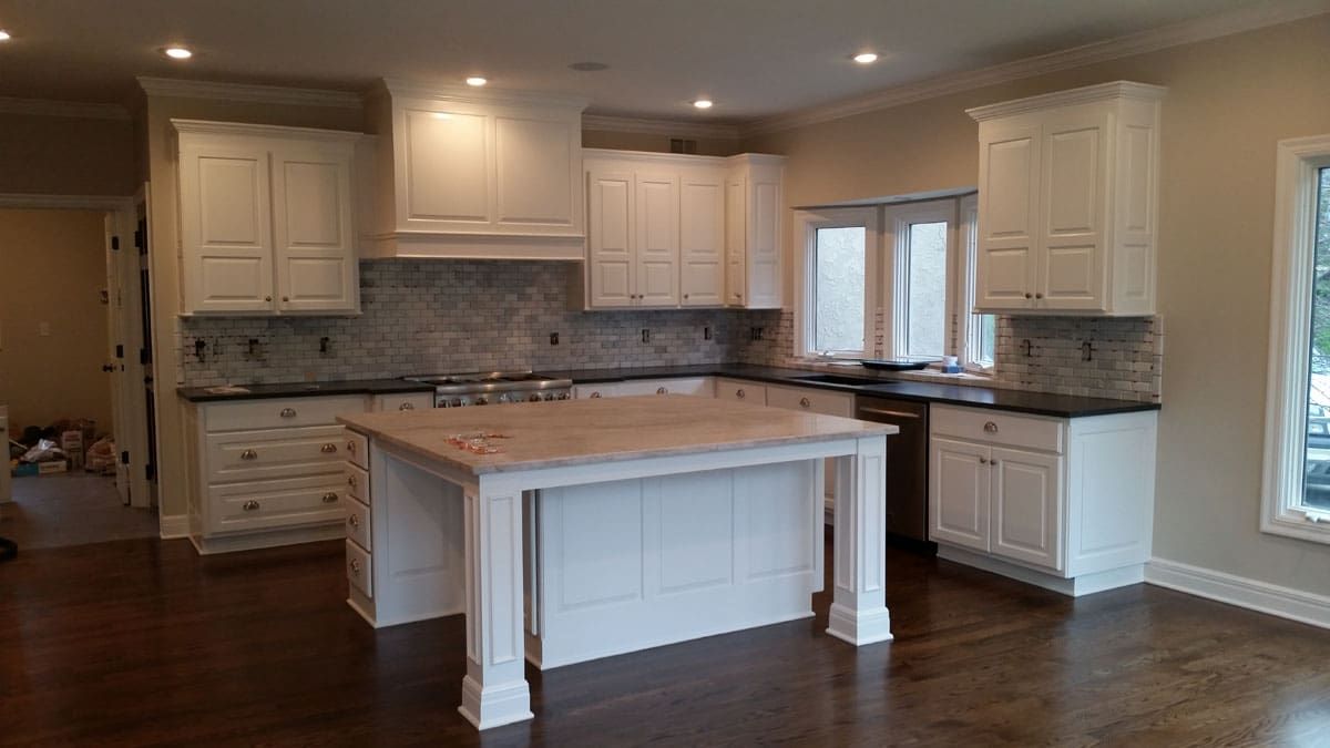 A kitchen with white cabinets and a large island in the middle.