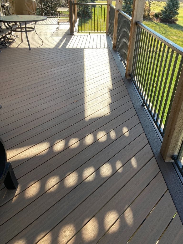 A wooden deck with a metal railing and a table and chairs on it.