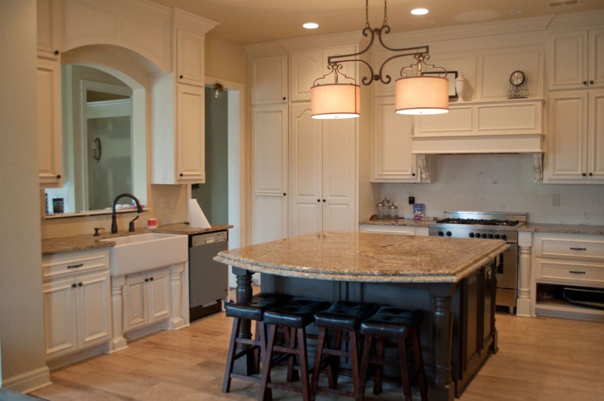 A kitchen with white cabinets and a large island in the middle
