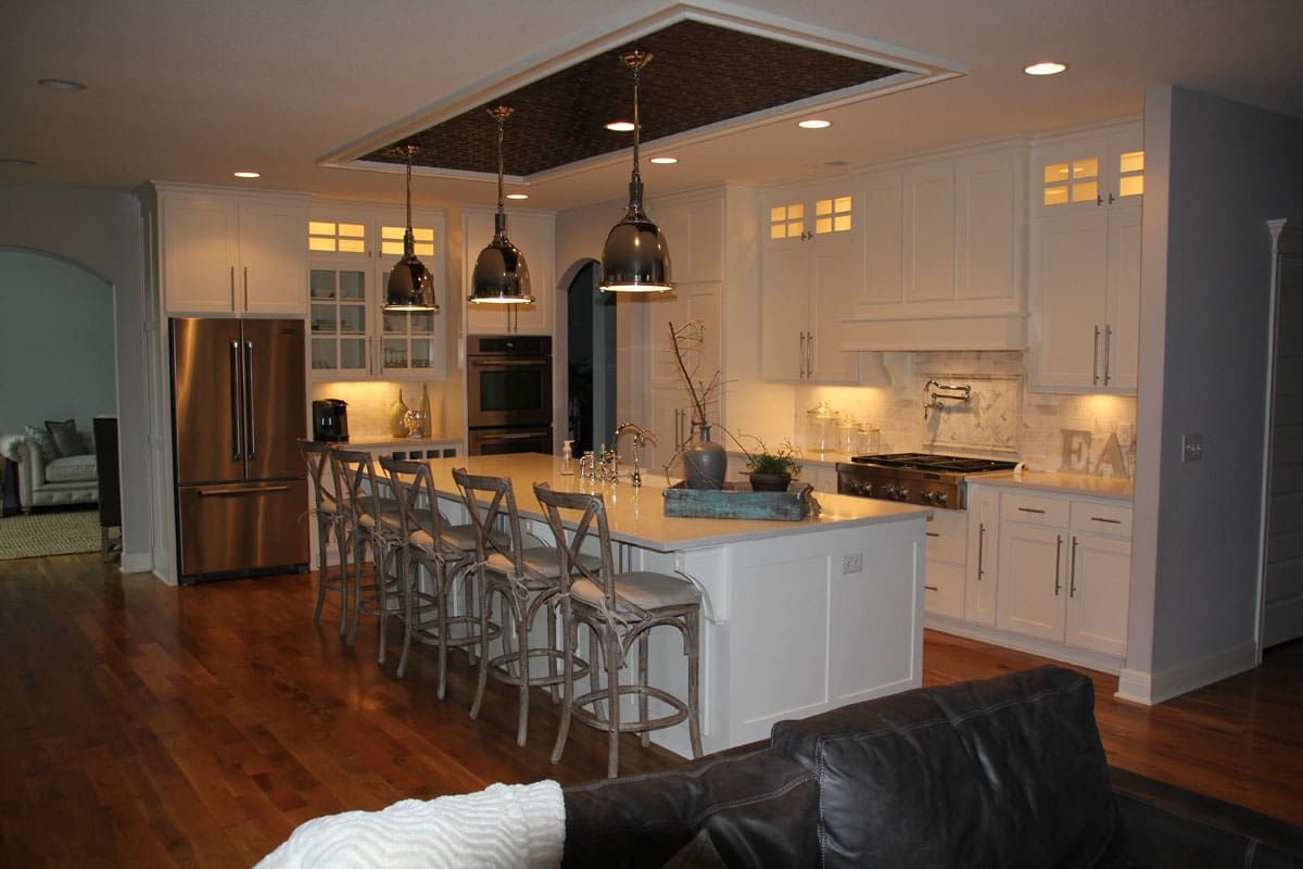 A kitchen with white cabinets , stainless steel appliances and a large island.
