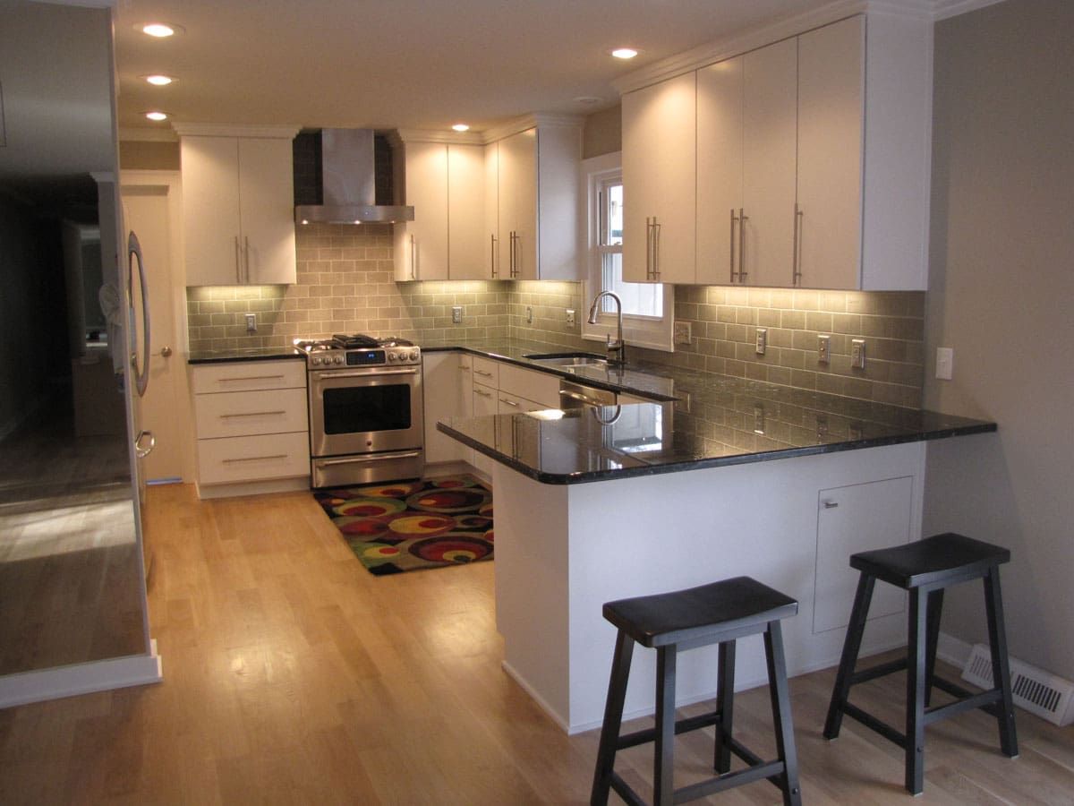 A kitchen with white cabinets and black counter tops