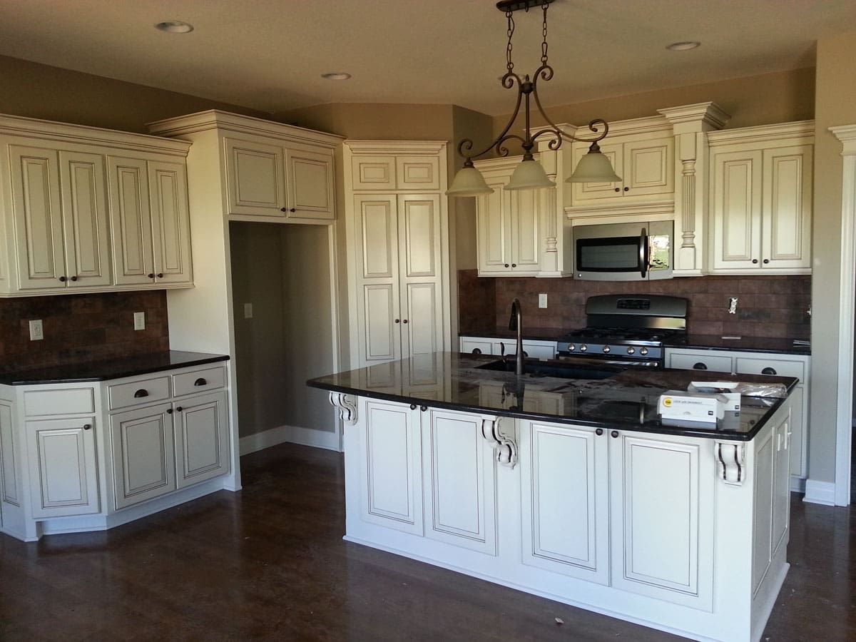 A kitchen with white cabinets and black counter tops