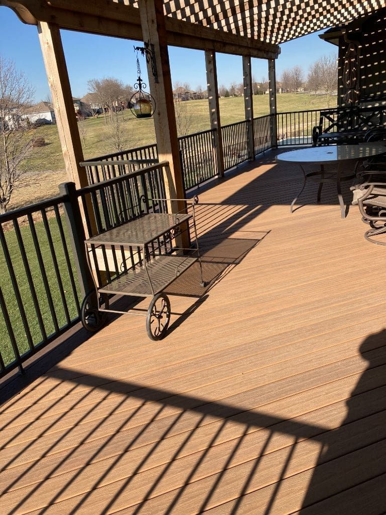 A wooden deck with a table and chairs under a pergola.