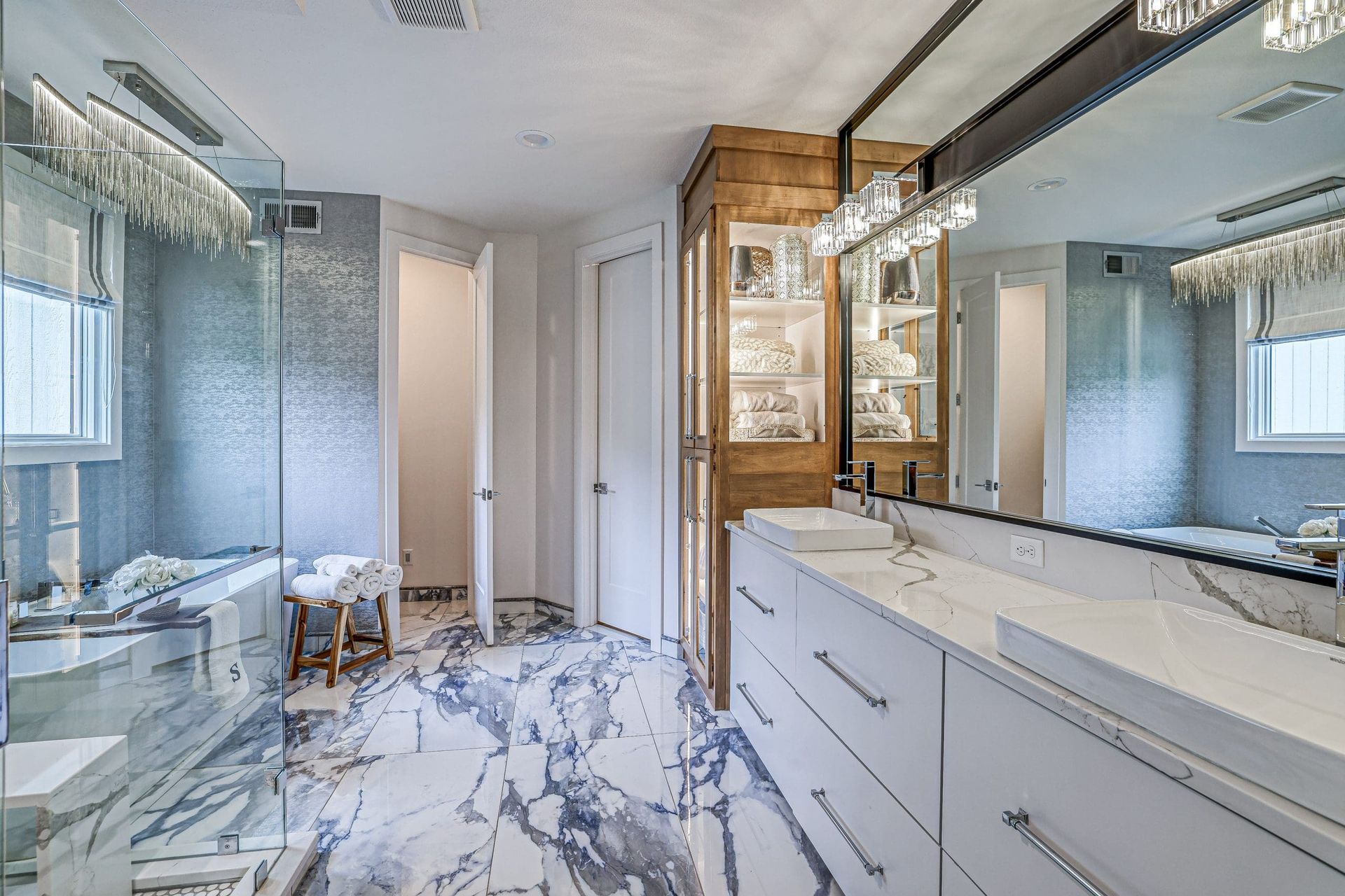 A bathroom with two sinks , a large mirror and a walk in shower.