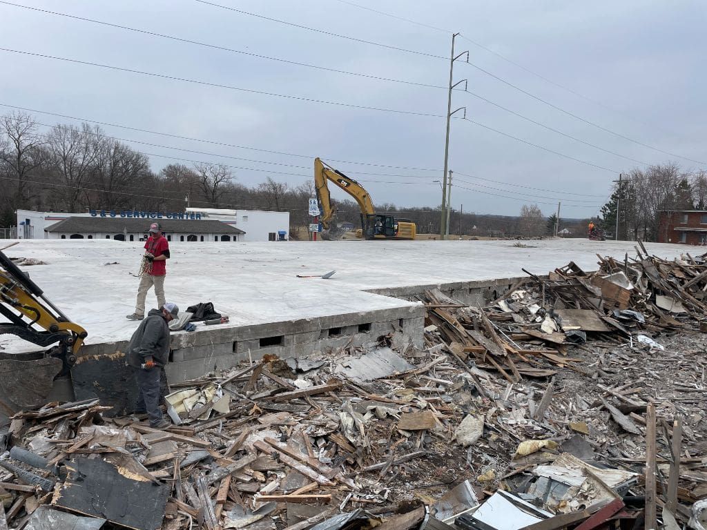 A man is standing in the middle of a pile of rubble.