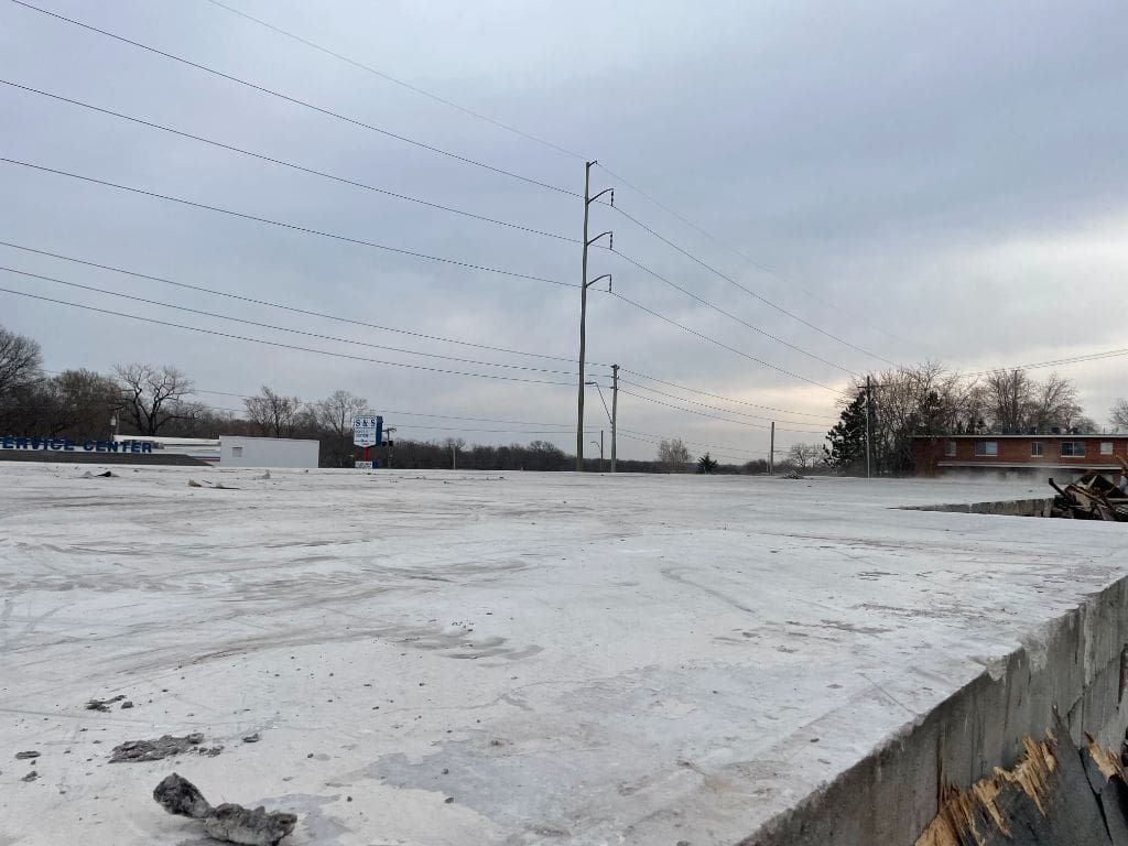 A snowy field with power lines and a building in the background