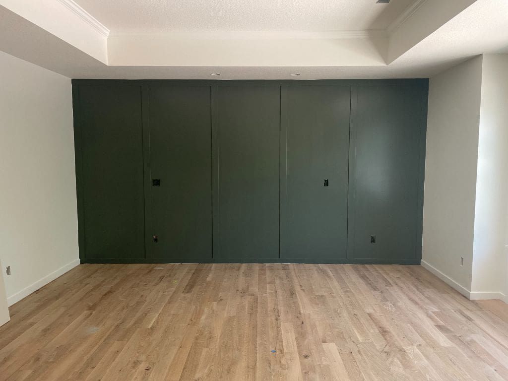 An empty room with a wooden floor and a green wall.
