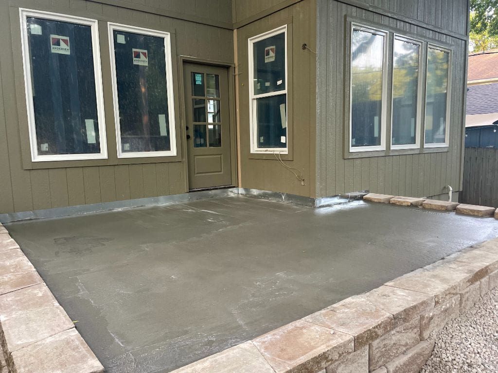 A concrete patio is being built in front of a house.