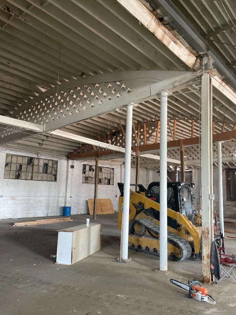 An empty warehouse with a bulldozer and a chainsaw.