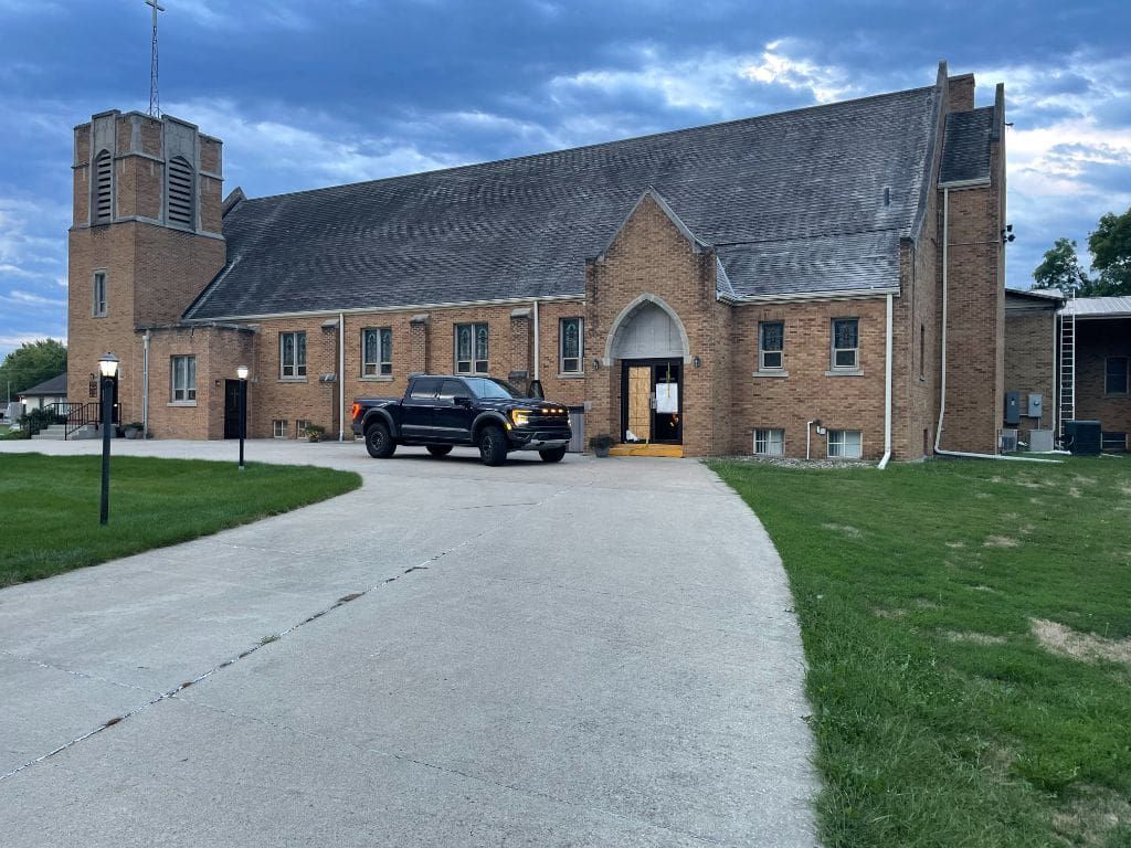 A black truck is parked in front of a large brick building.