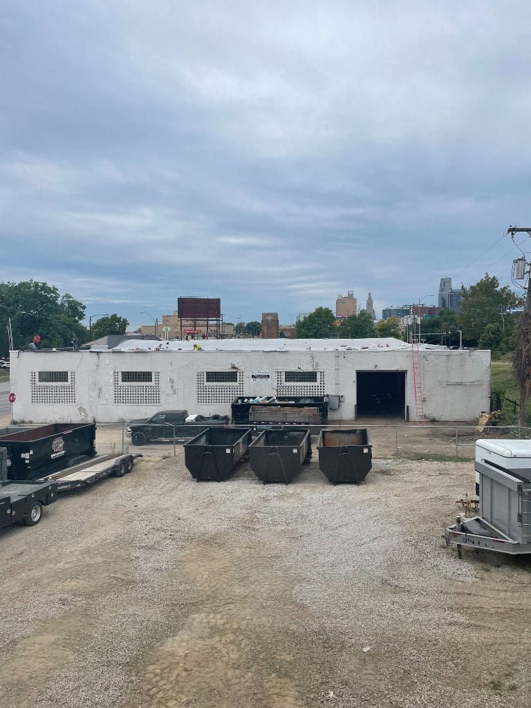 A large white building with a lot of dumpsters in front of it.