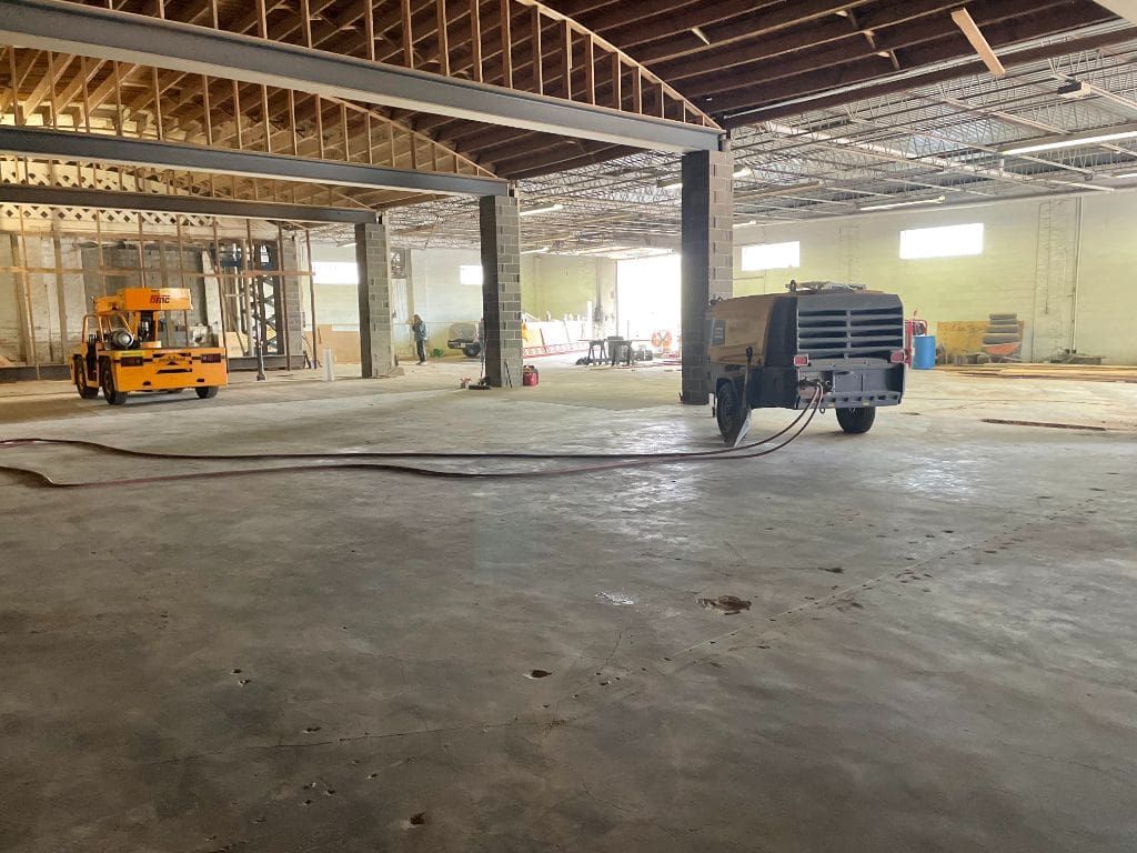 A large warehouse with a forklift and a machine in it.
