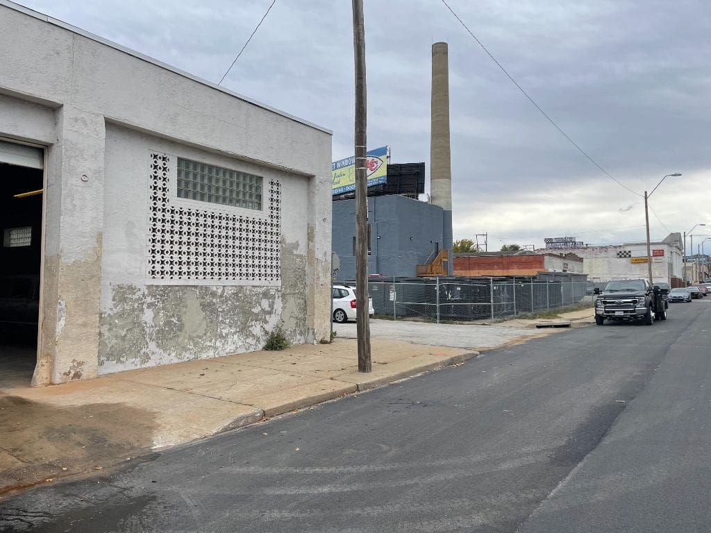 A truck is driving down a street next to a building.