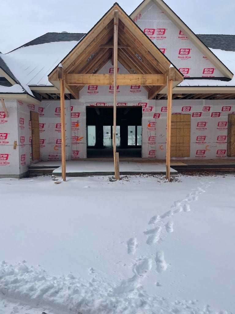 A house under construction is covered in snow.