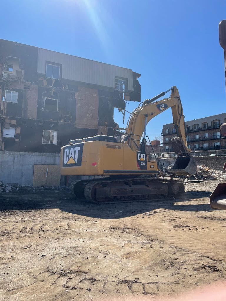 A cat excavator is being used to demolish a building.
